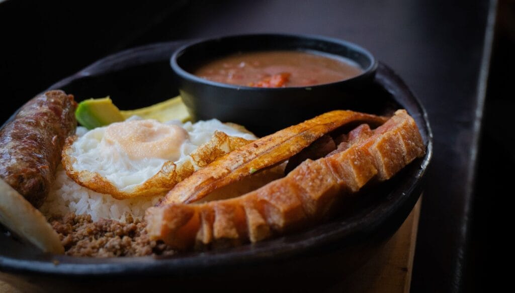 Bandeja Paisa completa con chicharrón, huevo frito, chorizo, carne molida, arroz y un plato de frijoles, comida típica de Salento, Quindío.