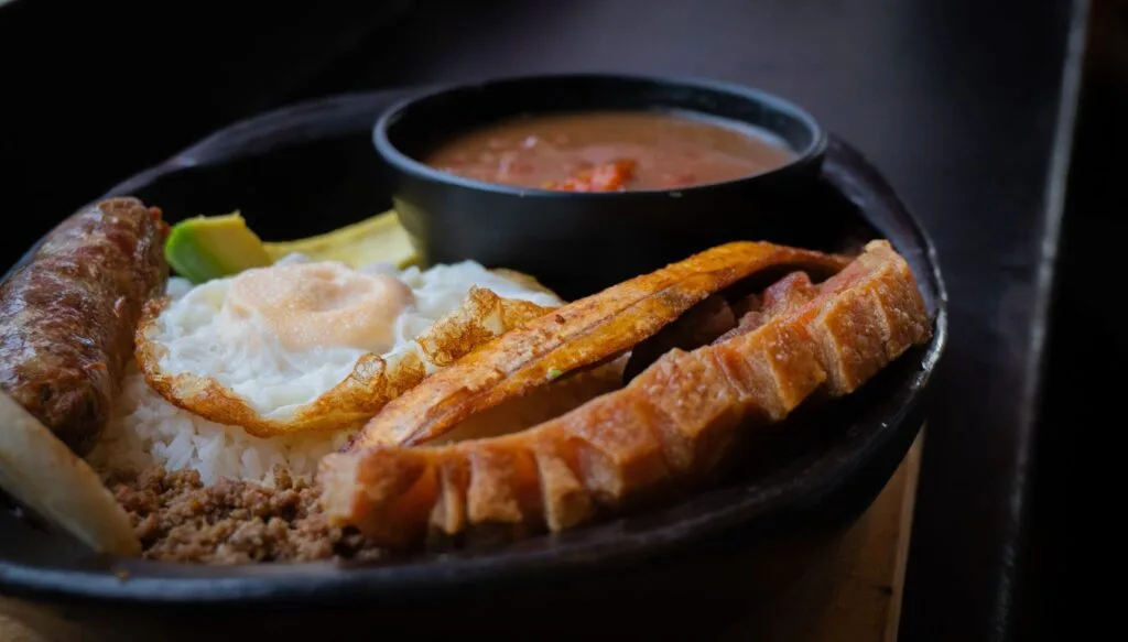 Bandeja Paisa completa con chicharrón, huevo frito, chorizo, carne molida, arroz y un plato de frijoles, comida típica de Salento, Quindío.