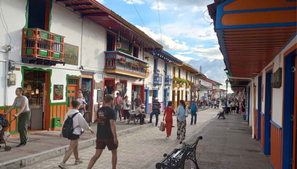 Calle Real (Carrera 6) de Salento, Quindío, con arquitectura colonial, balcones coloridos, pavimento de piedra y turistas caminando, centro comercial del Eje Cafetero.