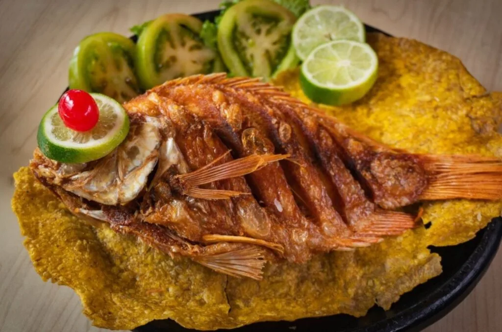 Plato de Mojarra frita entera dorada, acompañada de arroz con coco y patacón, un plato popular en los restaurantes de Salento, Quindío.
